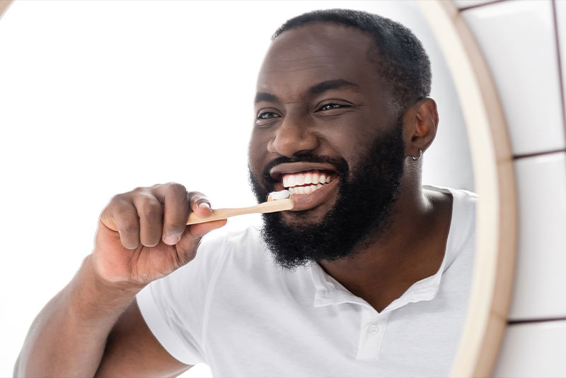 person smiling brightly and brushing their teeth