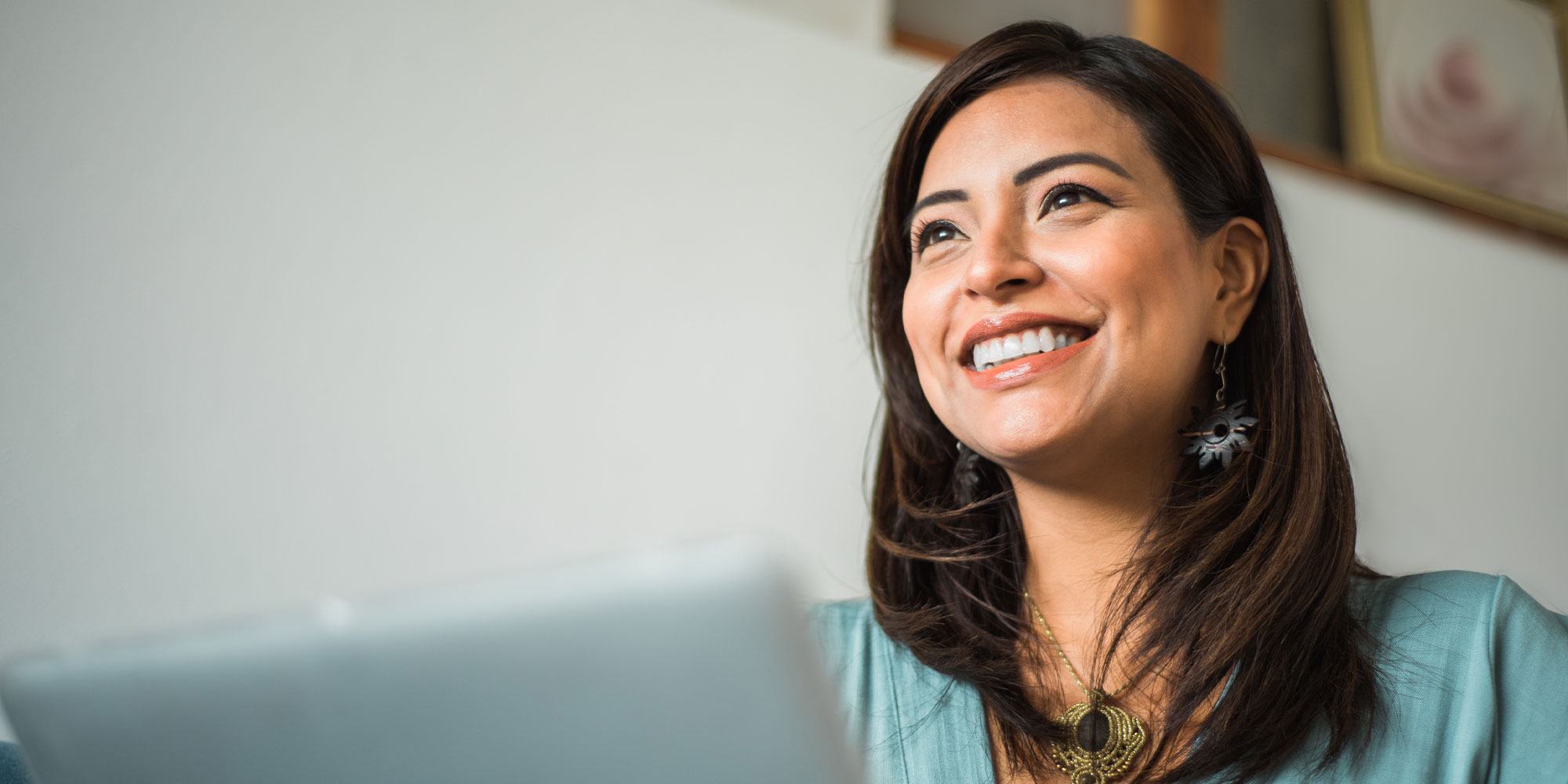 Close up of smiling woman looking aside with laptop at home