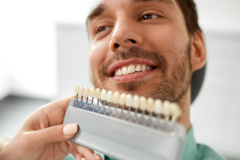 male having teeth samples being compared for their teeth whitening