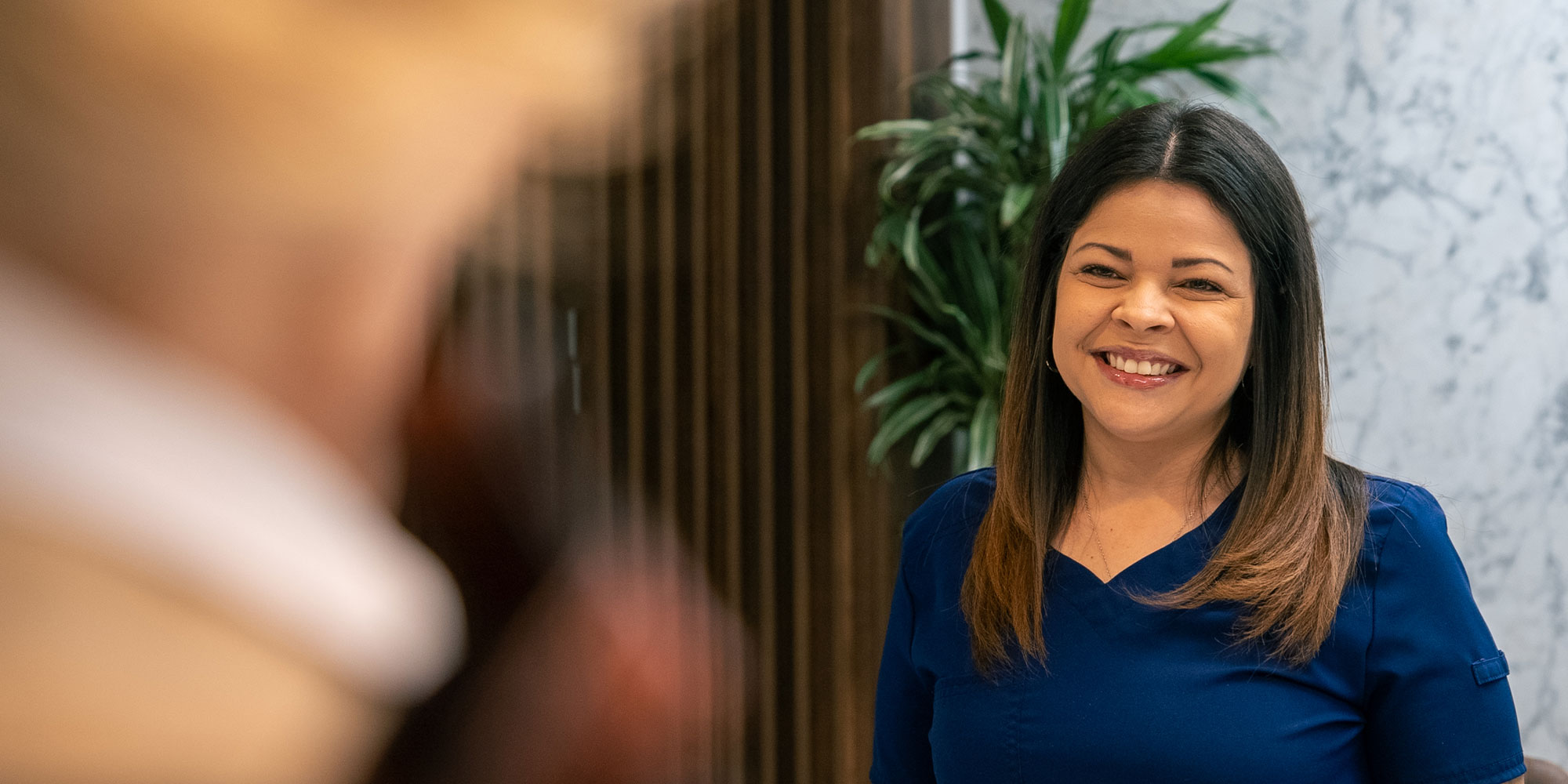 staff member smiling brightly while helping a dental patient at the front office