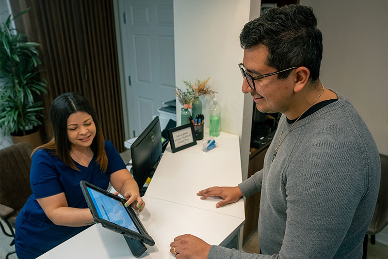 patient going over with staff member dental finance information within at the front desk